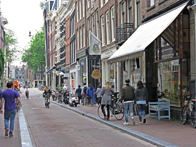 Casual stroll along a cobbled street in the Nine Streets shopping area of Amsterdam with local shops and cyclists.